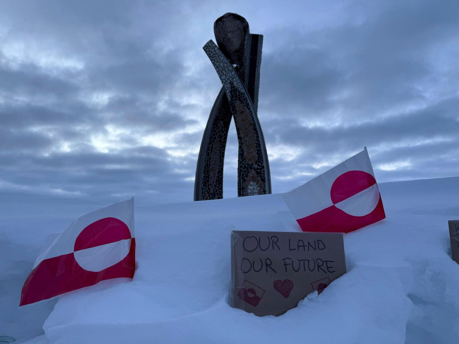 Two Greenland flags and a sign that reads "Our land, Our future" are seen in front of the Inussuk statue, a sculpture marking the start of Self Governance, during a visit by US Vice President JD Vance in Nuuk Greenland.